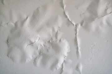 White paint swollen from moisture on the ceiling close-up