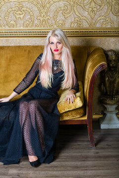 Blonde in black lace dress sits on couch with yellow upholstery in room