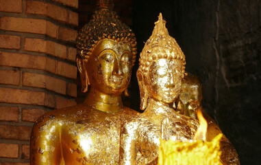 Buddha statues in the soft light of a candle flame in a Buddhist temple