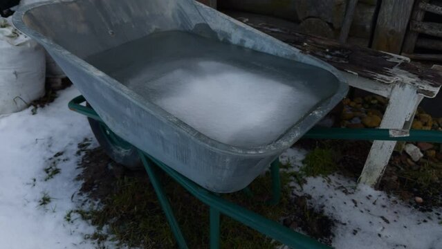 A wheelbarrow filled with water is sitting in the snow