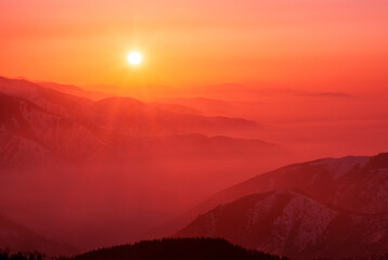 Magical view of a mountain valley shrouded in a light haze at sunset; magical atmosphere of a...
