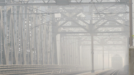 Magical atmosphere of a foggy conditions; a giant railway bridge and a departing train dissolving in the foggy haze