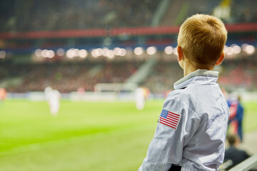 Little boy watch soccer game at stadium, rear view