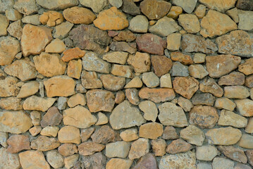 The texture of natural wild stones neatly laid out in the form of a fence.