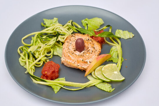 Red fish roll with shredded and sliced vegetables and fruits on plate