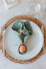 Easter themed table setting, with napkin folded in shape of bunny ears and an egg in the middle