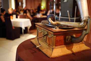 Old gramophone and people in restaurant, focus on gramophone, translation of text - gramophone...