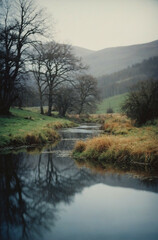 A winding river flows through a misty valley, reflecting the surrounding trees and hills
