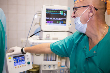  Doctor in uniform is standing near heartbeat monitor at the center of endosurgery and lithotripsy