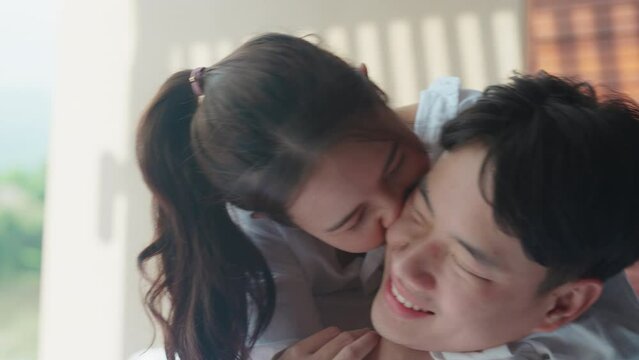 Young adult asia people happy lover flirt on cozy sofa bed hotel falling in love kiss hug beloved care trust. Sweet comfort asian lovers tender face to face man woman smile relax warm time date day.