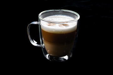 A glass of coffee on a black background. Latte or cappuccino