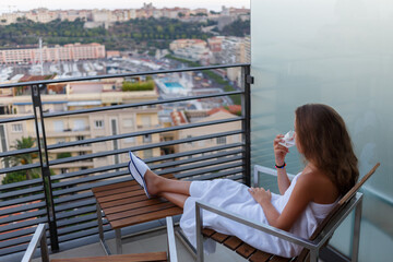 Girl dressed in towel sitting on balcony on background of bay of La Condamine