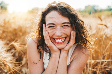 Happy beautiful woman smiling at camera in a wheat field - Delightful female enjoying summertime...