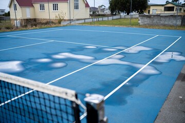 wet tennis court with puddles on a public sport court in australia