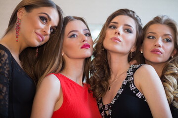 Closeup portrait of four beautiful women, focus on girl in red dress