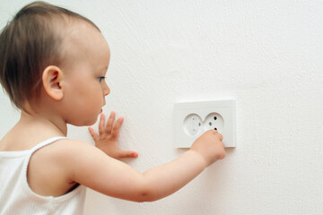 Child put finger in socket. Baby touching the power socket.