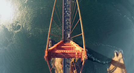 Vehicles ride by Golden Gate bridge at sunny day. Aerial view