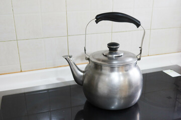 silver stainless steel pot kettle with Whistle function for boil water placing on the stove in kitchen