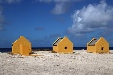 Yellow slave huts against blue sky - historic site on Bonaire Island, Caribbean Netherlands - 755737278