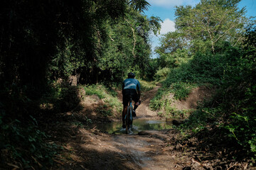 Fototapeta premium A middle aged bearded cyclist riding his gravel bike in the woods.
