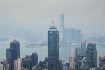 Tall Center tower on sea shore with ships in business area in mist in Hong Kong, China, view from Queen Garden