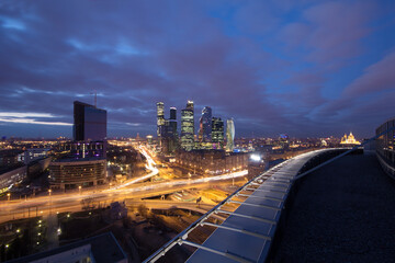 Highway, roof at night and modern skyscrapers in Moscow, Russia, long exposure