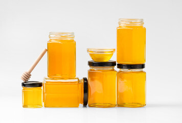 Glass jars with honey one on top of the other on a white background.