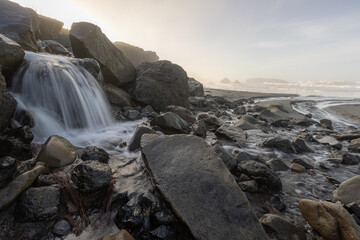 A rocky shoreline with a stream of water flowing through it