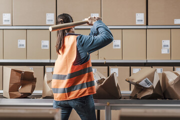 Angry rebellious worker smashing boxes in the workplace