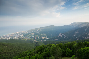 Fog coast of sea, town and green mountains at hot summer day