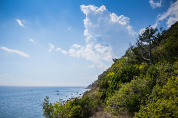 Fototapeta na wymiar Beautiful coast of sea with rocks and green mountain at hot summer day