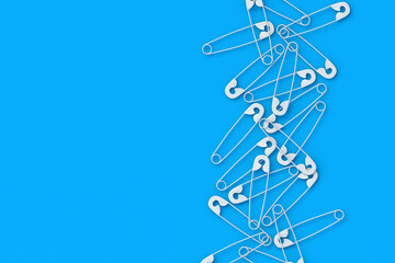 Many scattered safety pins on blue background. Tool for sewing. Top view. Copy space. 3d render