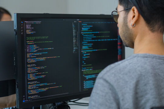 Asian promt engineer develope coding app with software data sitting in front of computer monitor at office