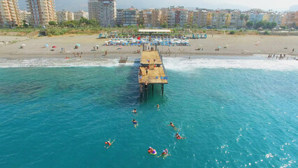 Many people swim in sea near pier on city beach at summer sunny day. Aerial view videoframe