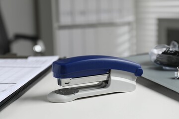 Stapler on white table indoors, closeup view