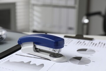 Stapler and document on table indoors, closeup
