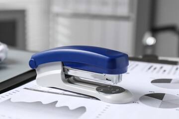Stapler and document on table indoors, closeup