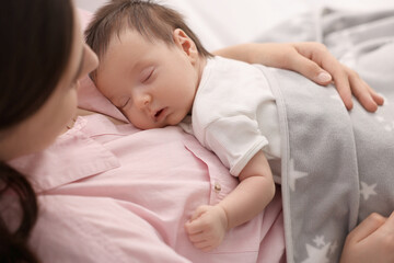Fototapeta na wymiar Mother with her sleeping newborn baby in bed, closeup
