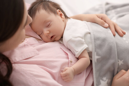 Mother with her sleeping newborn baby in bed, closeup