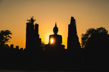 A silhouette of a Buddha statue is cast in the sun