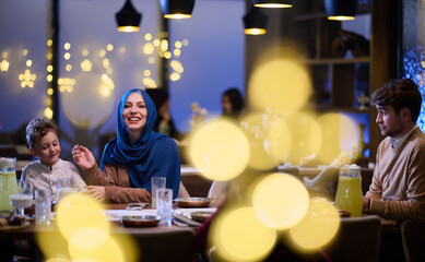 In a modern restaurant, an Islamic couple and their children joyfully await their iftar meal during...