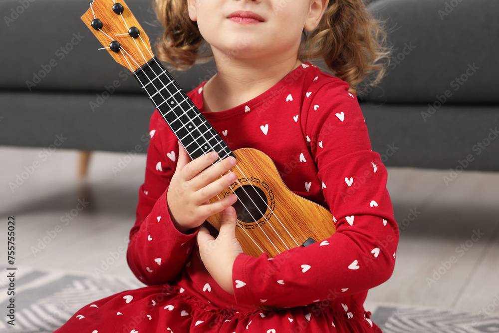 Sticker Little girl playing toy guitar at home, closeup