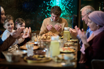 In a modern restaurant setting, a European Islamic family comes together for iftar during Ramadan, engaging in prayer before the meal, uniting tradition and contemporary practices in a celebration of