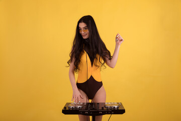 Beautiful dj girl in a yellow-black swimsuit in yellow glasses with black headphones and.with DJ...