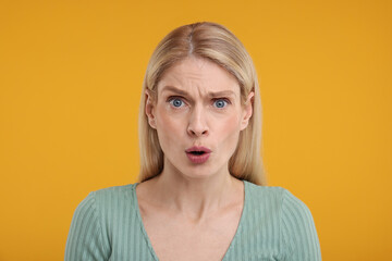 Portrait of surprised woman on yellow background