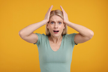 Portrait of surprised woman on yellow background