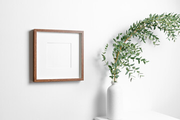 Square frame mockup for artwork, quote or print presentation on white wall with fresh eucalyptus...