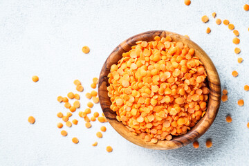 Red lentils in wooden bowl on white background. Top view.
