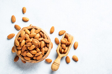 Almond nuts in wooden bowl at white background.