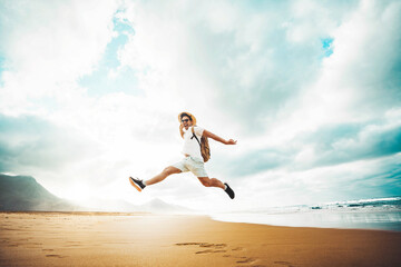 Happy traveler with hands up jumping at the beach - Delightful man enjoying success and freedom...